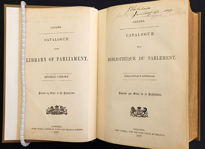 Open book, showing the bilingual title pages from the 1857 catalogue of the Library of Parliament.