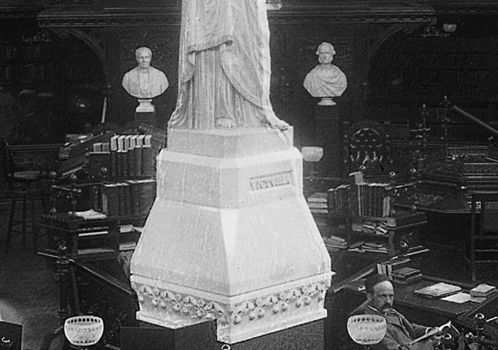 Photo noir et blanc montrant l'intérieur de la Bibliothèque vers 1895, les bustes de sir Étienne-Paschal Taché et de John Sandfield Macdonald sont visibles en arrière plan