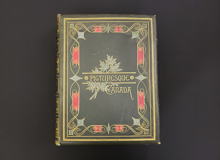 A green leather volume decorated with a red and green pattern. A maple leaf motif frames the book’s title.